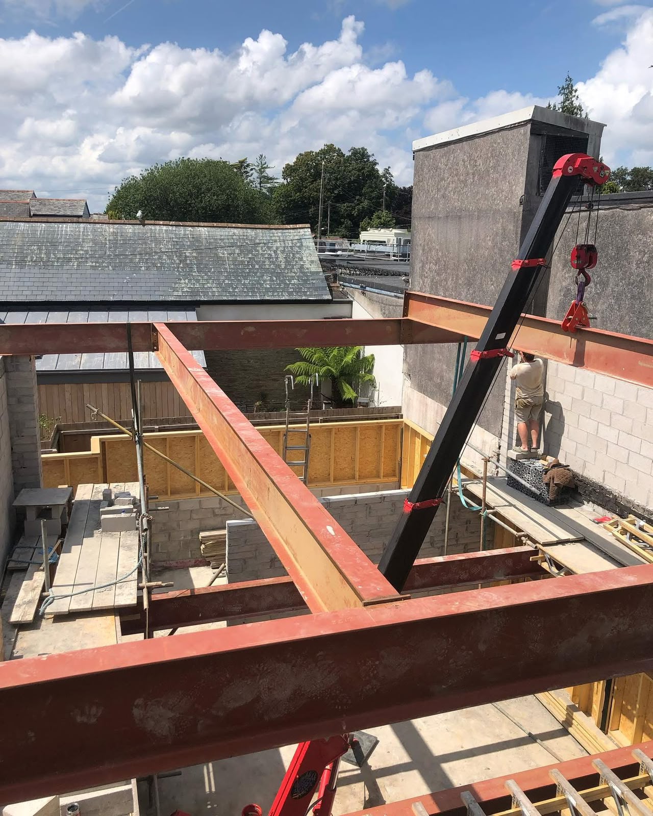 Spider crane lifting a structural steel beam into position on a commercial refurbishment