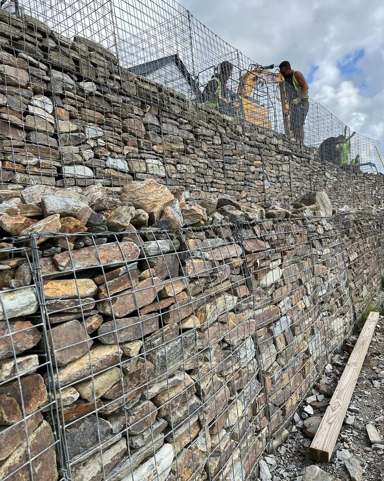Gabion basket retaining structure being filled beside an excavator in Calstock, Cornwall