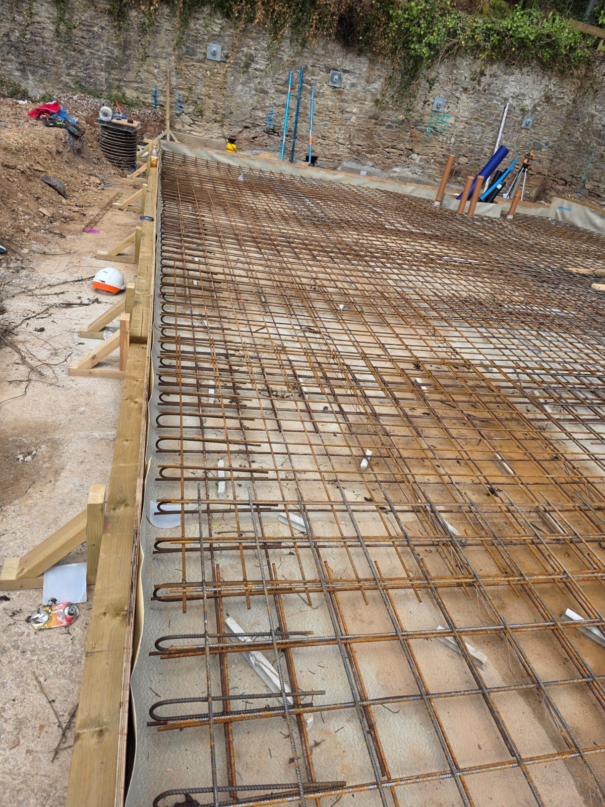 Reinforced concrete base by CC Construction Ltd: steel mesh, formwork and service pipes set ready for a slab pour in Cornwall